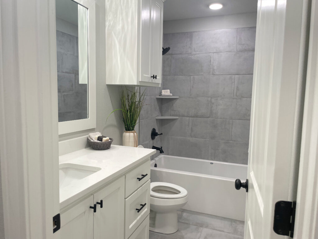 White bathroom vanity and counter with light grey veining and black hardware