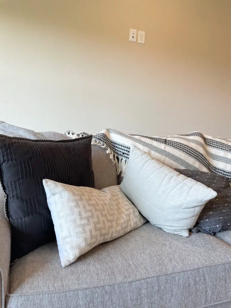 geometric patterned grey, white, and black pillows on grey linen couch