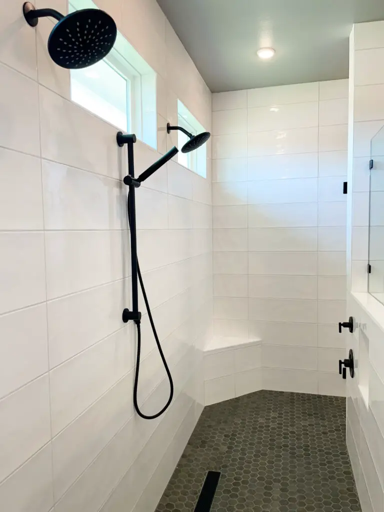 large scale white tile similar to a big subway tile in walk in shower with black accents