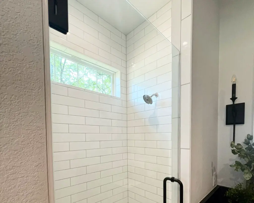 subway tile shower with black and silver accents