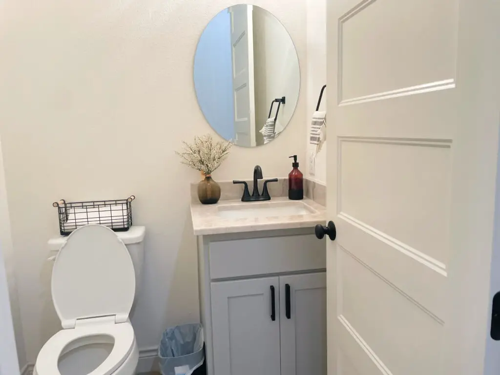 oval mirror over vanity in neutral half bath