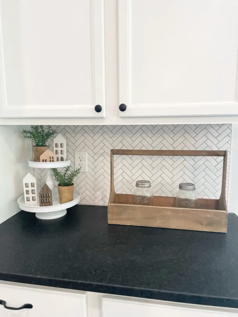small scale white chevron tile backsplash and solid black countertops in farmhouse kitchen