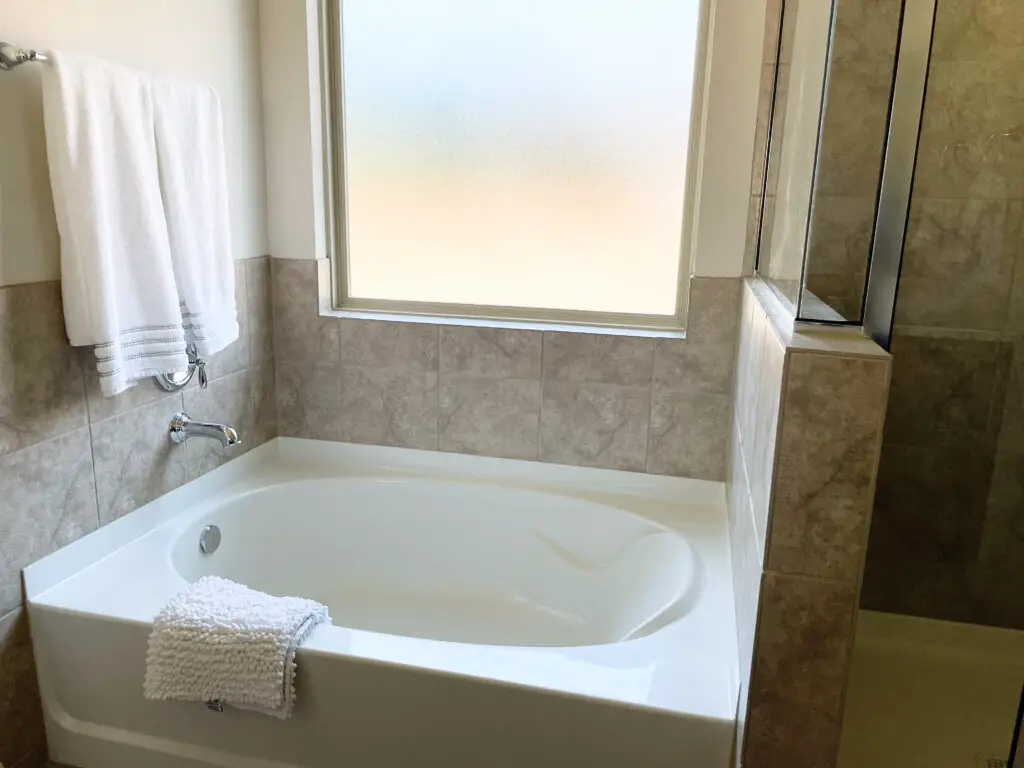 dated square greige tile around bathtub and shower
