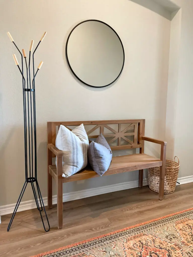 minimalism in an entryway with a round mirror above a bench
