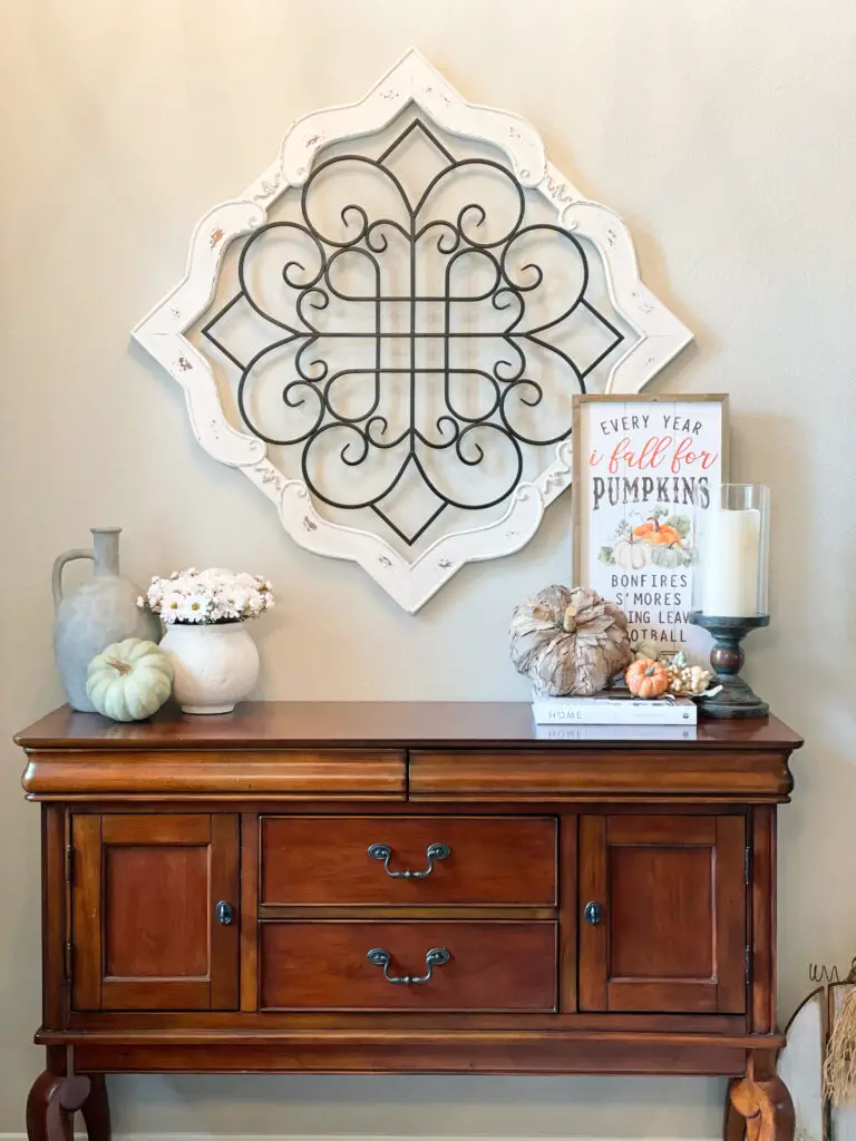 Brown entryway table with decorative objects and wall art above it