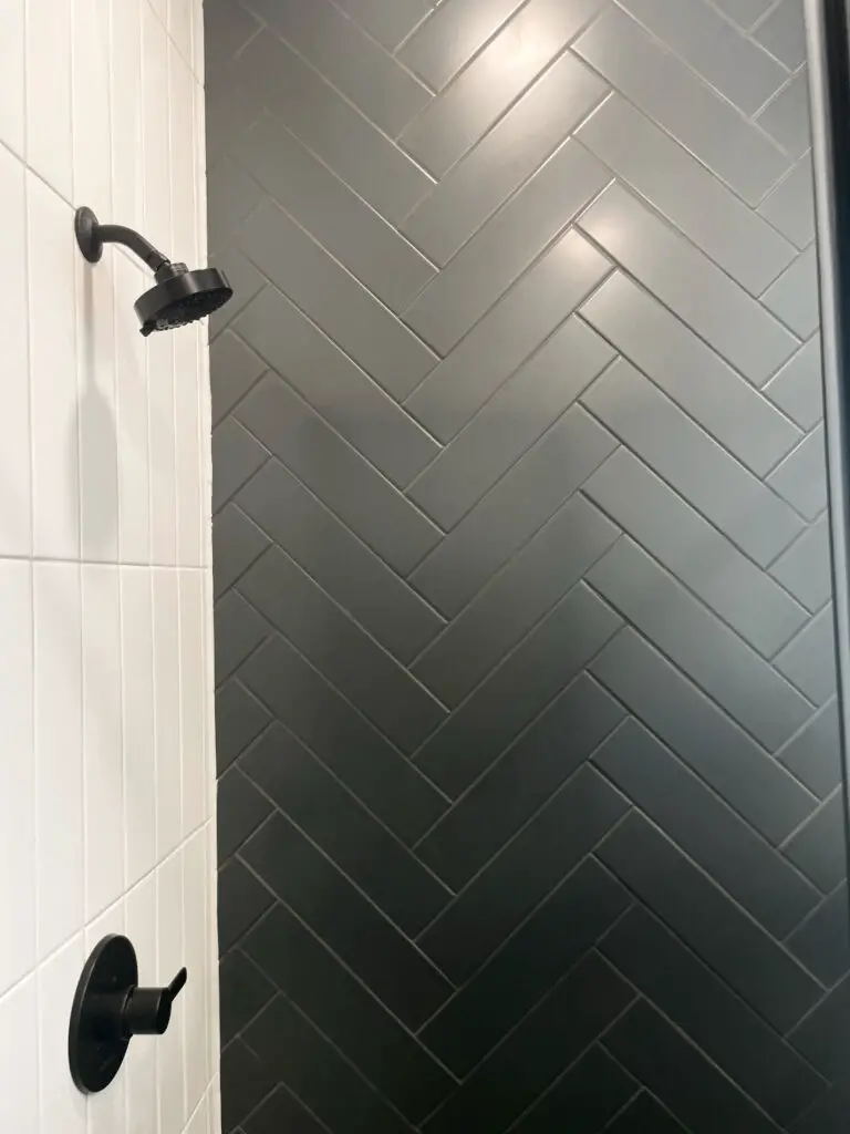 Black subway tile in chevron pattern on one wall of a black and white shower