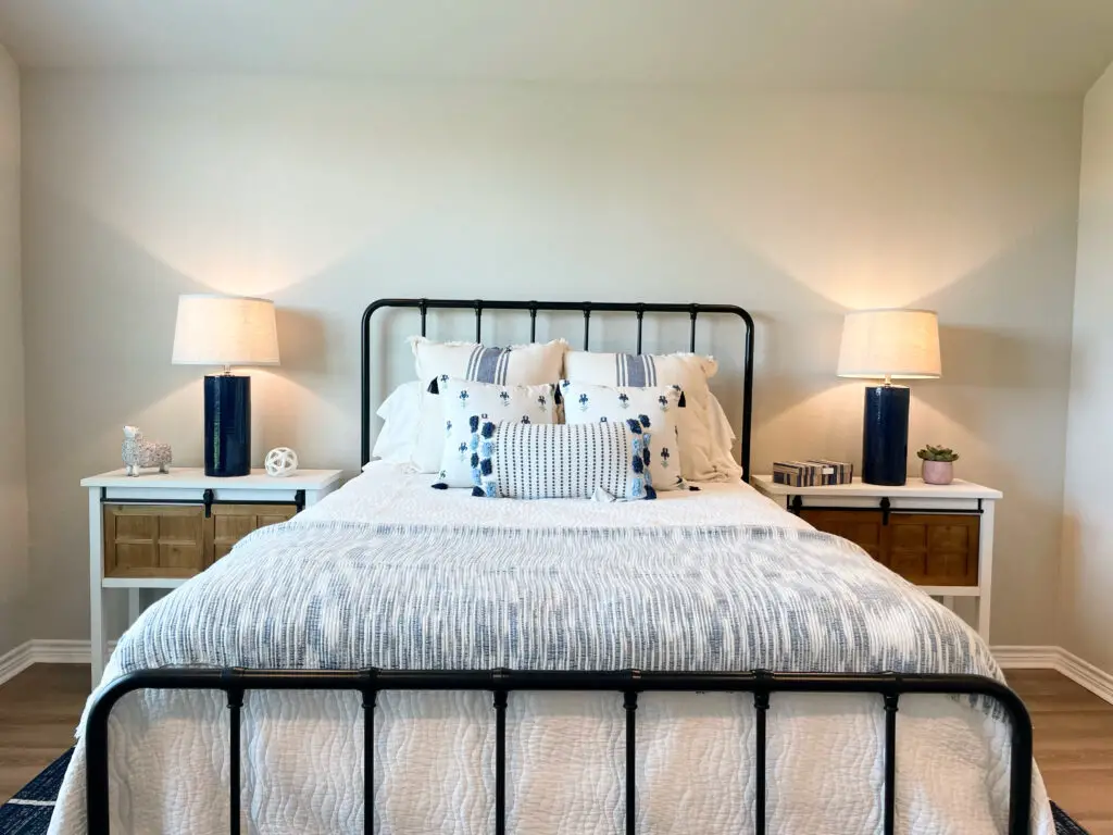 Wrought iron bed frame with large nightstands and blue and white bedding