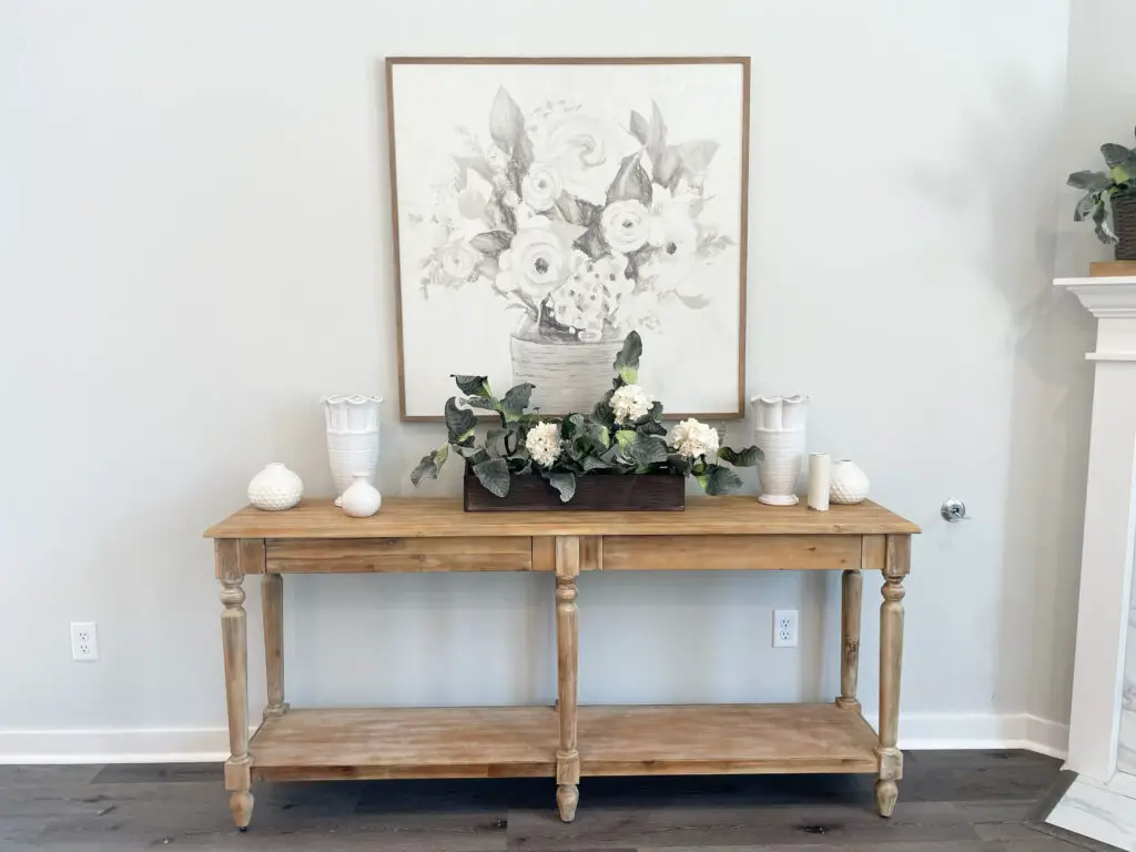 Light sideboard with dark wooden box filled with white flowers surrounded by farmhouse decor