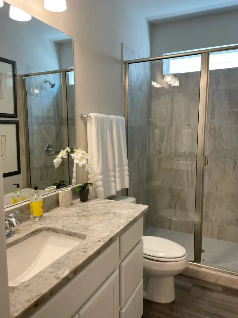 grey and white bathroom design with tile rack over the toilet