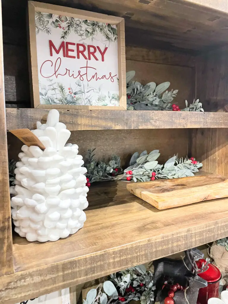 White pinecone next to Christmas decorations on a shelf