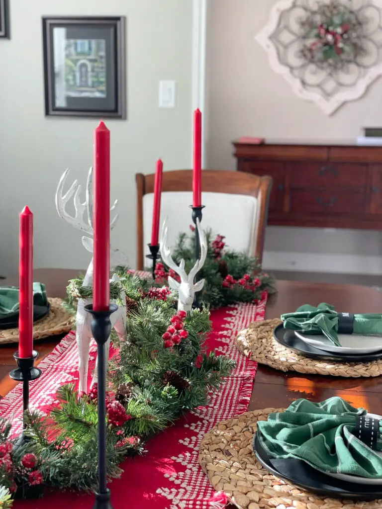 Black candlesticks in garland centerpiece with white deer and red accents