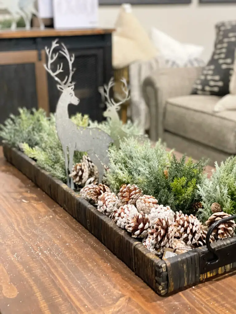 Long tray filled with greenery and pinecones with two silver deer