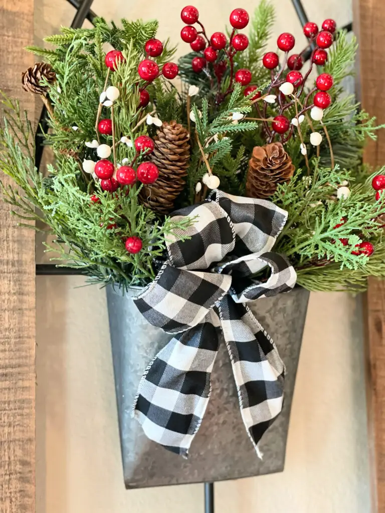 tin basket with Christmas greens and bow on wooden wall decoration