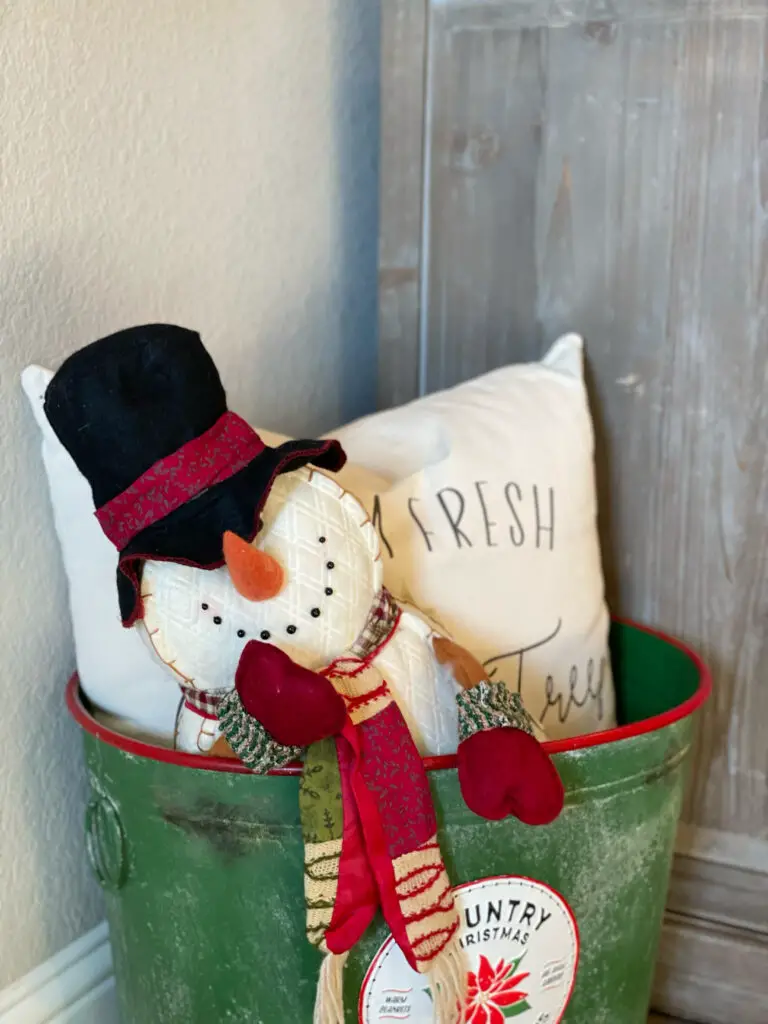 snowman and Christmas pillow in a holiday bucket