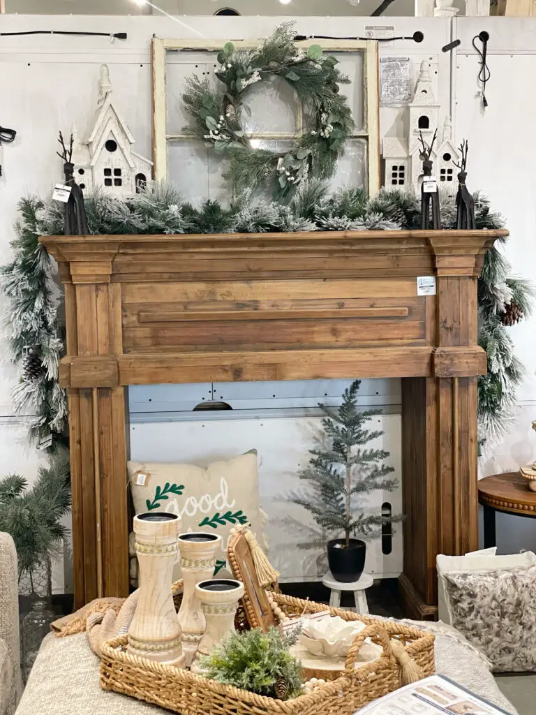 Faux fireplace mantle decorated with Christmas greenery and white and black holiday accents