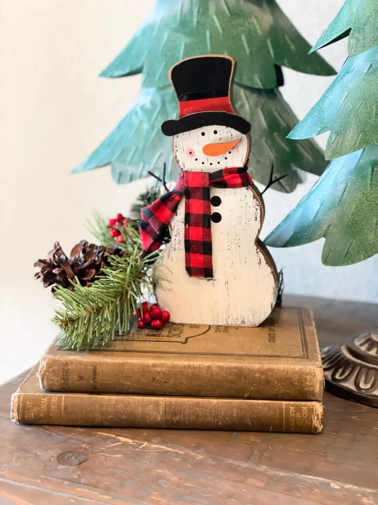 small greenery pick next to snowman in Christmas arrangement
