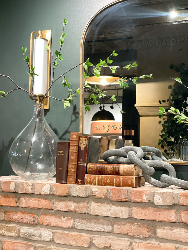 Farmhouse fireplace styling with antique books, large chain and decorative vase