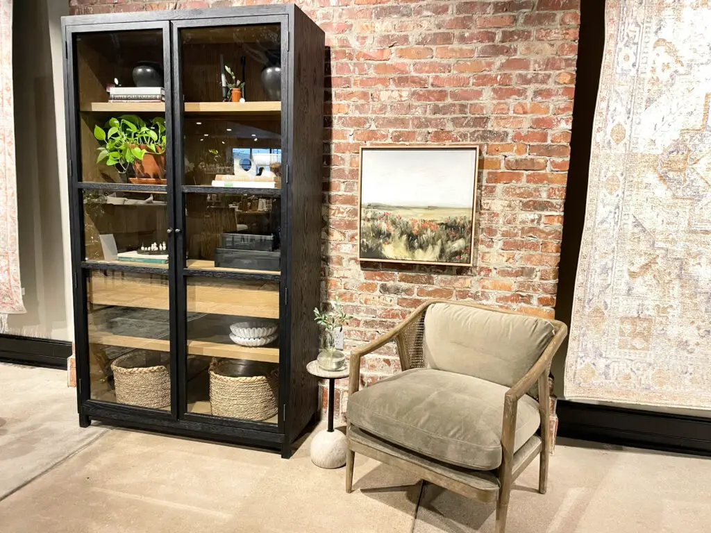 landscape painting in seating area with large cabinet next to it