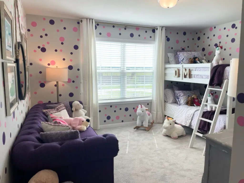 purple couch in pink and purple kids room with bunk beds and polka dots